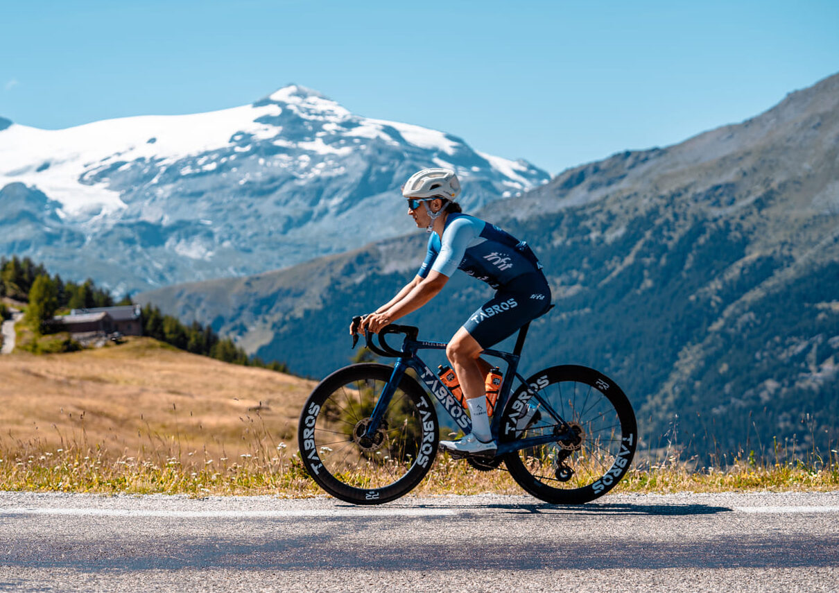 Mattia in sella a bici TABROS su strada, paesaggio di montagne nello sfondo